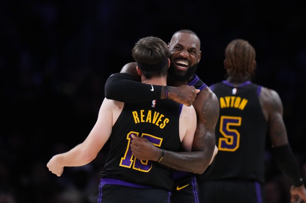 Lakers guard Austin Reaves (15) is embraced by teammate LeBron...