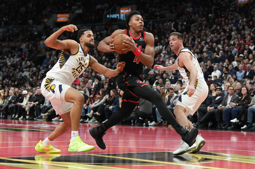 Toronto Raptors forward Scottie Barnes (4) drives to the net between Indiana Pacers forward Jeremiah Robinson-Earl (25) and guard T.J. McConnell (9) during first half NBA Cup basketball action in Toronto on Wednesday, Nov. 26, 2025. (Chris Young/The Canadian Press via AP)