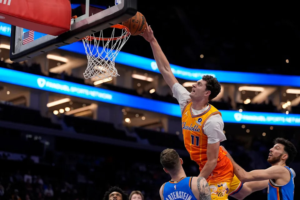 Nov 15, 2025; Charlotte, North Carolina, USA; Charlotte Hornets center Ryan Kalkbrenner (11) goes for the dunk over Oklahoma City Thunder center Isaiah Hartenstein (55) during the first quarter at Spectrum Center. Mandatory Credit: Jim Dedmon-Imagn Images