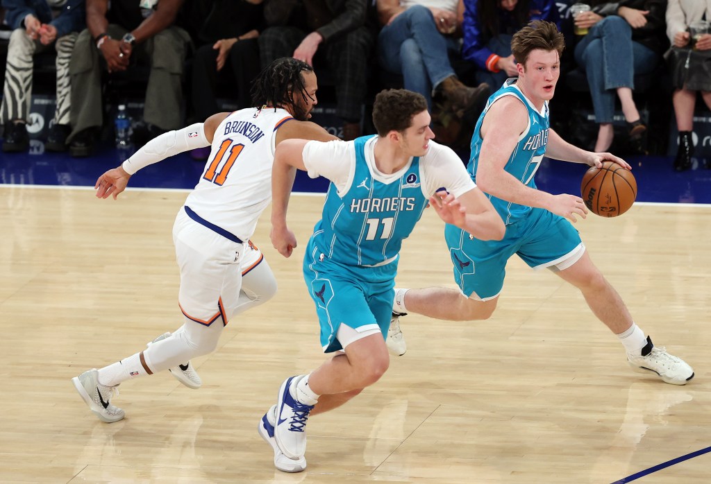 Kon Knueppel #7 dribbles with Ryan Kalkbrenner #11 of the Charlotte Hornets as Jalen Brunson #11 of the New York Knicks defends.