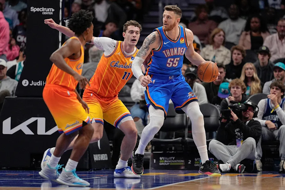 Nov 15, 2025; Charlotte, North Carolina, USA; Oklahoma City Thunder center Isaiah Hartenstein (55) handles the ball against Charlotte Hornets center Ryan Kalkbrenner (11) and guard Collin Sexton (8) during the first half at Spectrum Center. Mandatory Credit: Jim Dedmon-Imagn Images