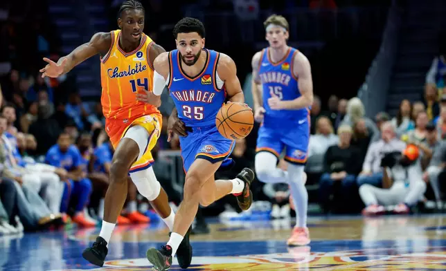 Oklahoma City Thunder guard Ajay Mitchell (25) pushes the ball upcourt against Charlotte Hornets forward Moussa Diabate during the second half of an NBA basketball game in Charlotte, N.C., Saturday, Nov. 15, 2025. (AP Photo/Nell Redmond)