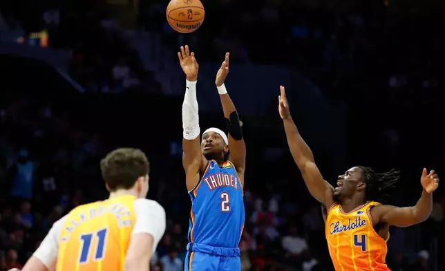 Oklahoma City Thunder guard Shai Gilgeous-Alexander (2) shoots against Charlotte Hornets guard Sion James (4) and center Ryan Kalkbrenner during the second half of an NBA basketball game in Charlotte, N.C., Saturday, Nov. 15, 2025. (AP Photo/Nell Redmond)