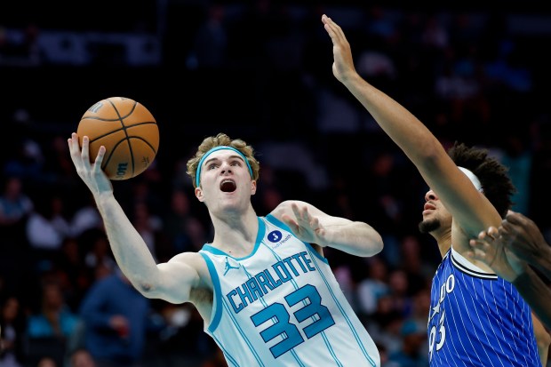 Charlotte Hornets guard Liam McNeeley (33) drives to the basket past Orlando Magic forward Noah Penda, right, during the first half of an NBA basketball game in Charlotte, N.C., Thursday, Oct. 30, 2025. (AP Photo/Nell Redmond)