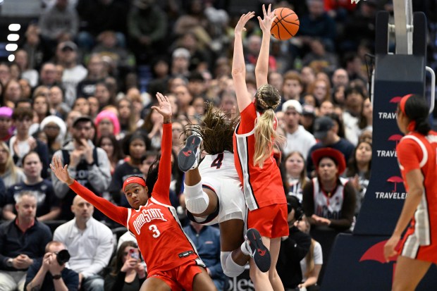 UConn guard Blanca Quinonez (4) is called for an offensive foul as Ohio State guard Kennedy Cambridge (3) and Ohio State forward Kylee Kitts defend in the first half of an NCAA college basketball game, Sunday, Nov. 16, 2025, in Hartford, Conn. (AP Photo/Jessica Hill)