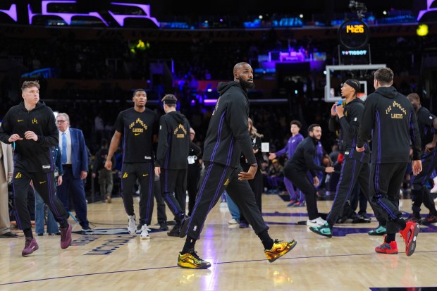 Lakers star LeBron James, center, warms up before their game...