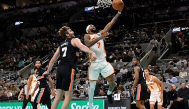 Atlanta Hawks guard Nickeil Alexander-Walker, center, goes to the basket against San Antonio Spurs center Luke Kornet during the first half of an NBA basketball game, Thursday, Nov. 20, 2025, in San Antonio. (AP Photo/Darren Abate)