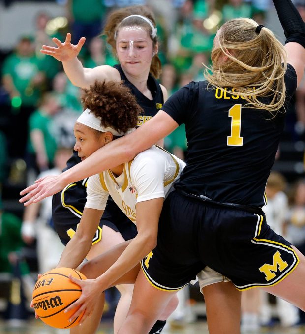 Notre Dame guard Hannah Hidalgo is pressured by Michigan guards Olivia Olson (1) and Syla Swords on Saturday, Nov. 15, 2025, in Detroit. (AP Photo/Al Goldis)
