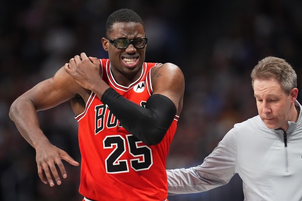 Chicago Bulls center Jalen Smith is ushered to the bench after his shoulder was injured while guarding Denver Nuggets center Nikola Jokić in the second half of an NBA basketball game Monday, Nov. 17, 2025, in Denver. (AP Photo/David Zalubowski)