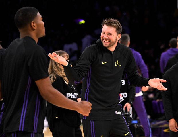 Lakers star Luka Doncic, right, smiles during warmups before their...