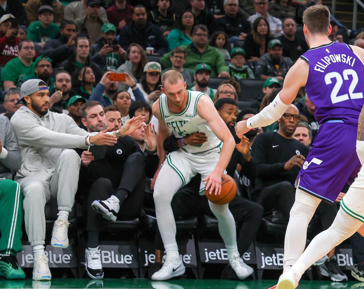 Jayson Tatum (left) might be injured but he was ready to lend a hand as Sam Hauser fell into the Celtics bench trying to save a loose ball.