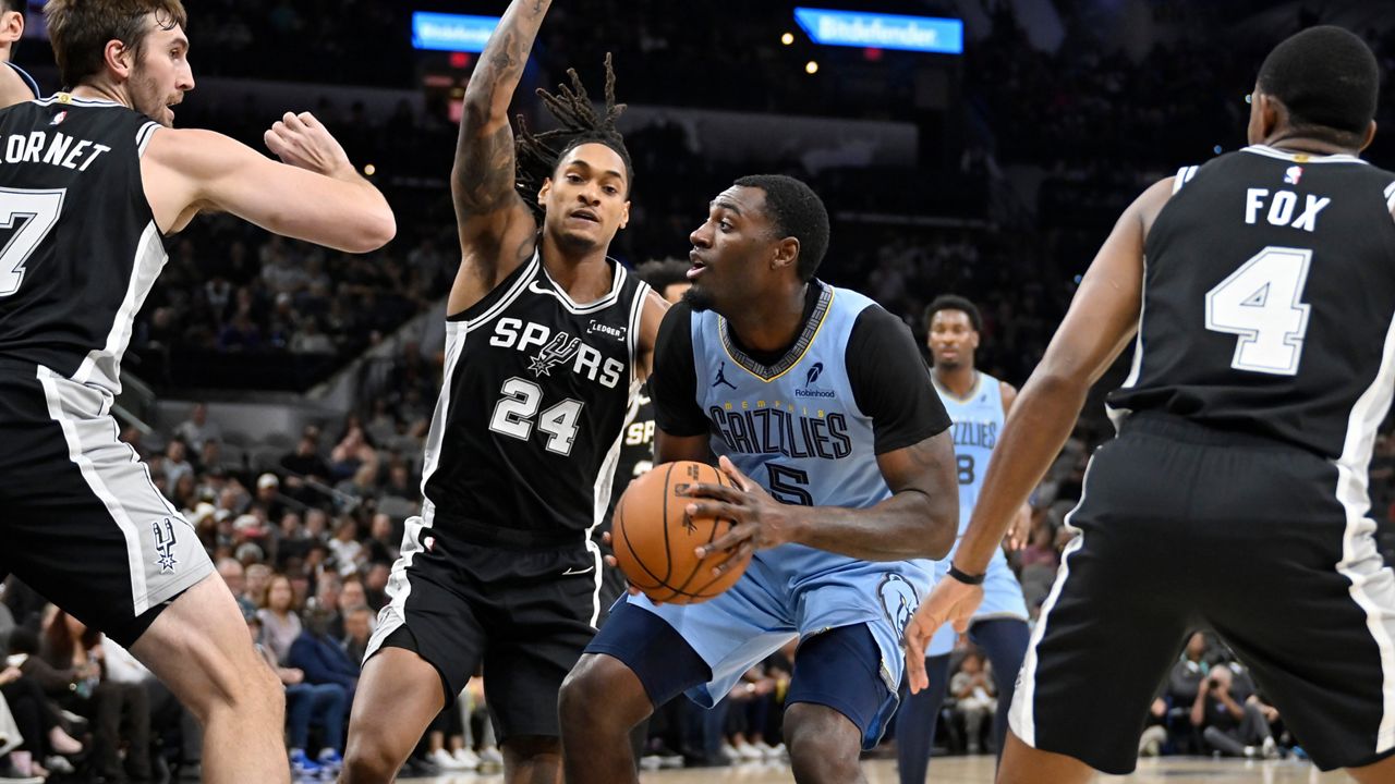 Memphis Grizzlies guard Vince Williams Jr. (5) drives against San Antonio Spurs guard Devin Vassell (24) and Spurs center Luke Kornet (7) during the first half of an NBA basketball game, Tuesday, Nov. 18, 2025, in San Antonio. (AP Photo/Darren Abate)