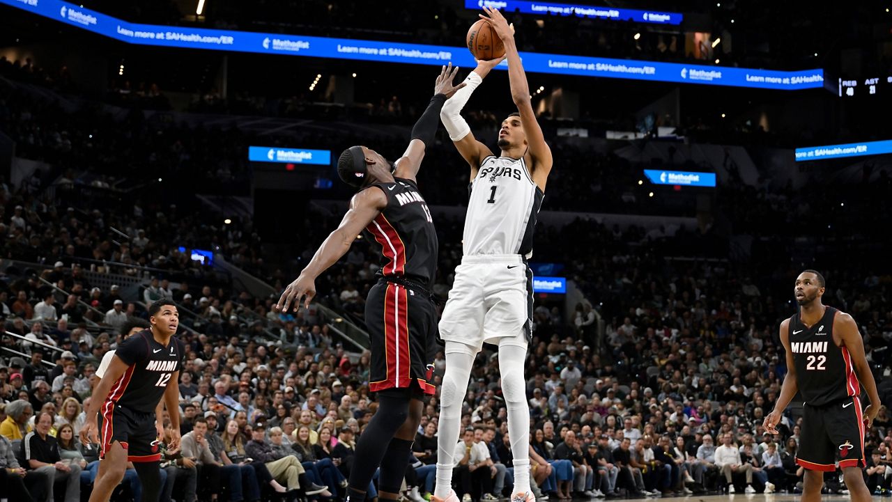 San Antonio Spurs center Victor Wembanyama (1) goes up to shoot against Miami Heat forward Bam Adebayo, center left, during the second half of an NBA basketball game, Thursday, Oct. 30, 2025, in San Antonio. (AP Photo/Darren Abate)