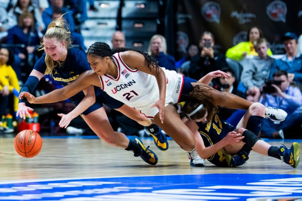Olivia Olson #1 of the Michigan Wolverines and Sarah Strong #21 of the Connecticut Huskies go for the loose ball during the first half of an Invesco QQQ Basketball Hall of Fame Women's Showcase game at Mohegan Sun on November 21, 2025 in Uncasville, Connecticut. (Photo by Joe Buglewicz/Getty Images)