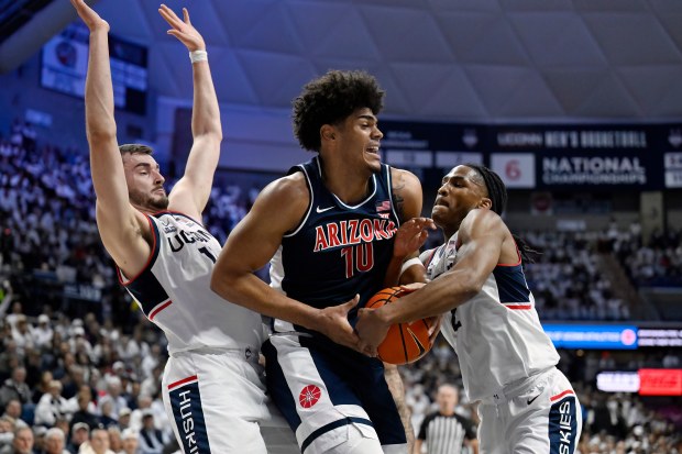 UConn forward Alex Karaban, left, and UConn guard Silas Demary Jr., right, pressure Arizona forward Koa Peat, center, in the first half of an NCAA college basketball game, Wednesday, Nov. 19, 2025, in Storrs, Conn. (AP Photo/Jessica Hill)