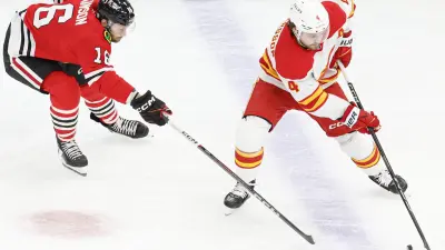 Jan 13, 2025; Chicago, Illinois, USA; Chicago Blackhawks center Jason Dickinson (16) battles for the puck with Calgary Flames defenseman Rasmus Andersson (4) during the second period at United Center. Mandatory Credit: Kamil Krzaczynski-Imagn Images