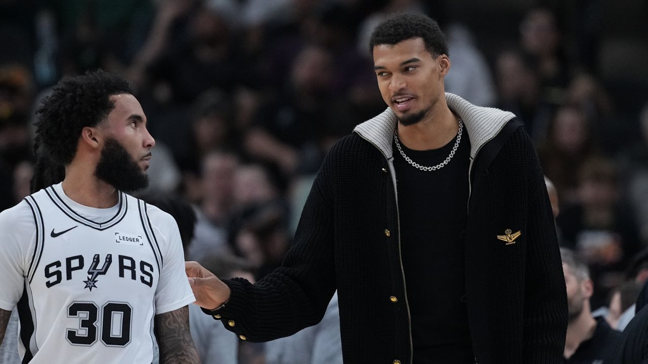 San Antonio Spurs forward Victor Wembanyama, right, talks with teamamte forward Julian Champagnie (30) during the first half of an NBA basketball game against the Sacramento Kings in San Antonio, Sunday, Nov. 16, 2025. (AP Photo/Eric Gay)