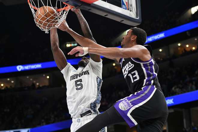 Memphis Grizzlies guard Vince Williams Jr. (5) dunks against Sacramento Kings forward Keegan Murray (13) in the first half of an NBA basketball game Thursday, Nov. 20, 2025, in Memphis, Tenn. (AP Photo/Brandon Dill)