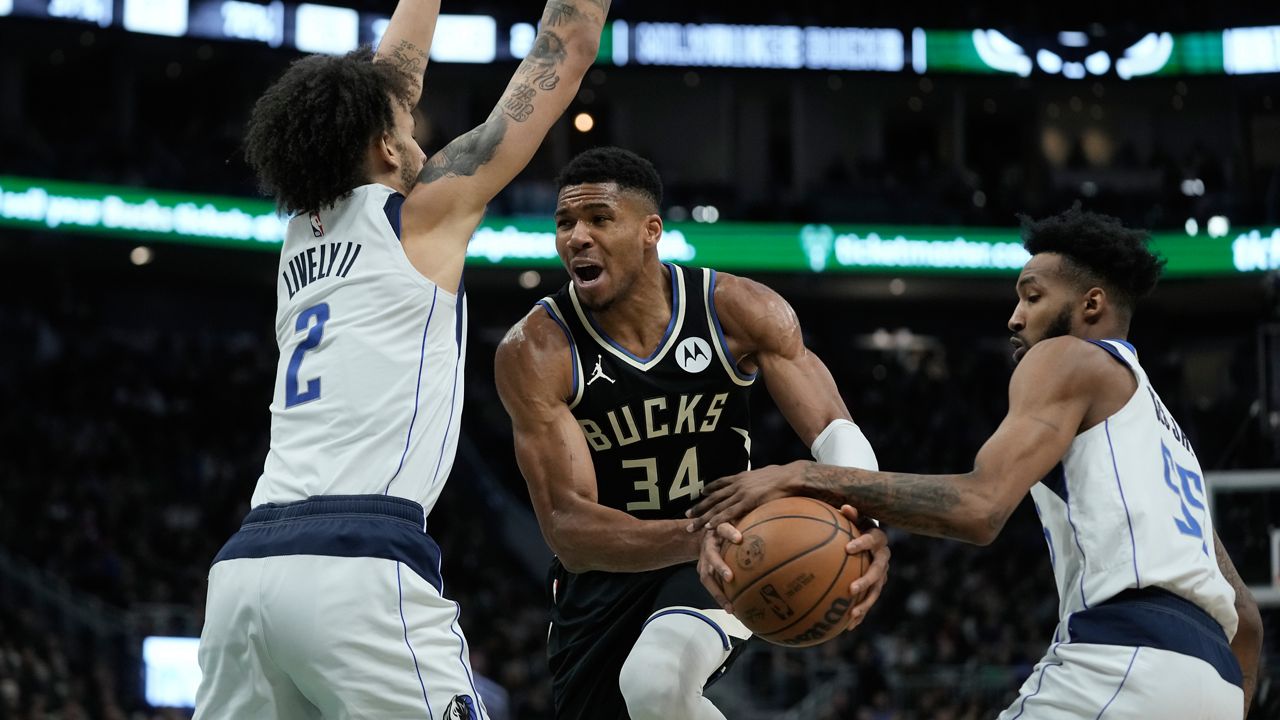 Milwaukee Bucks' Giannis Antetokounmpo is fouled driving between Dallas Mavericks' Derrick Jones Jr. and Dereck Lively II during the second half of an NBA basketball game Saturday, Nov. 18, 2023, in Milwaukee. The Bucks won 132-125. (AP Photo/Morry Gash)