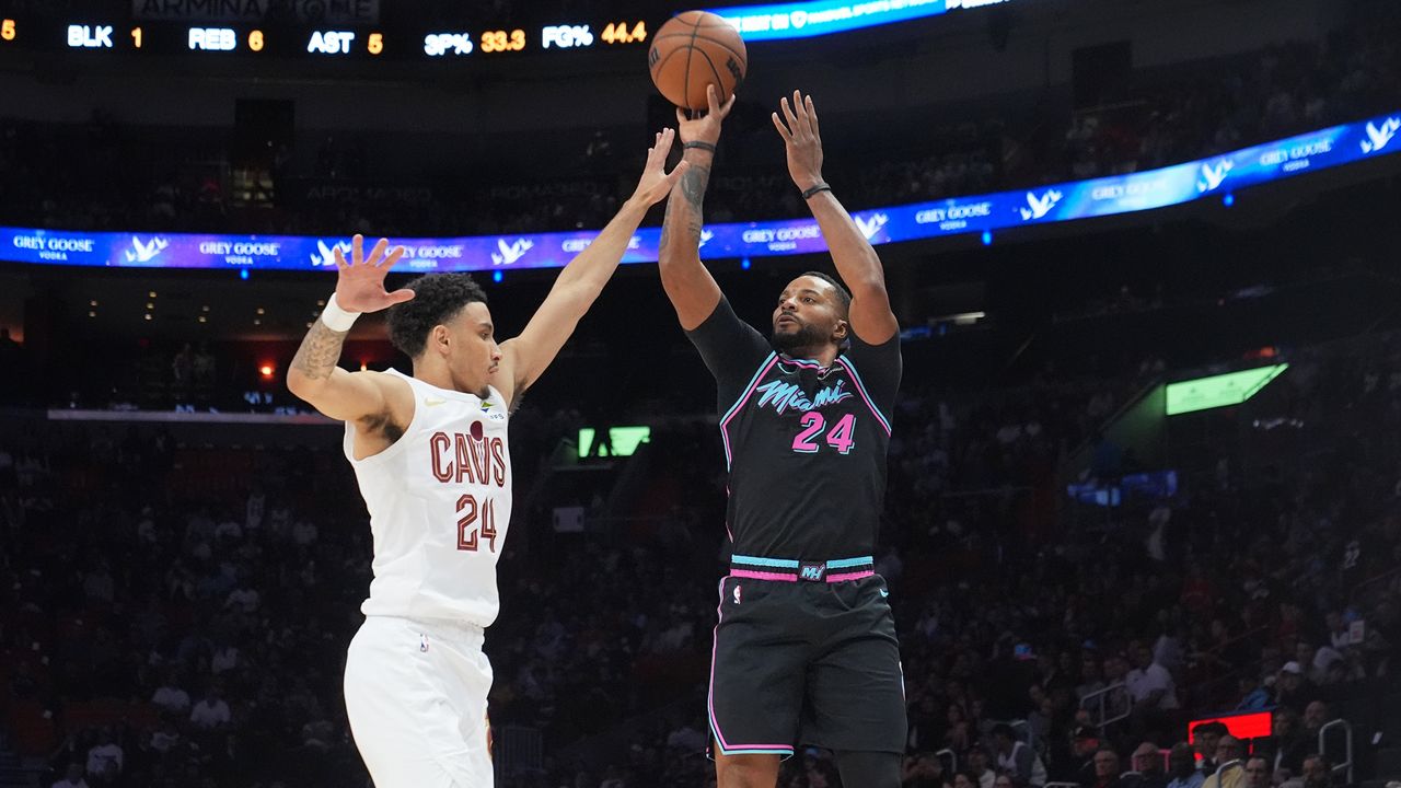 Miami Heat guard Norman Powell (24) aims a three-point shot as Cleveland Cavaliers guard Tyrese Proctor (24) defends during the first half of an NBA basketball game Wednesday, Nov. 12, 2025, in Miami. (AP Photo/Marta Lavandier)