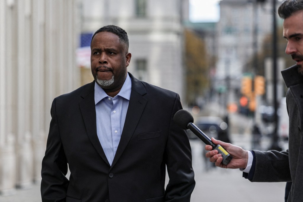 Former NBA player Damon Jones, in a suit, approaches a reporter with a microphone outside the Brooklyn Federal Courthouse after his arraignment hearing.
