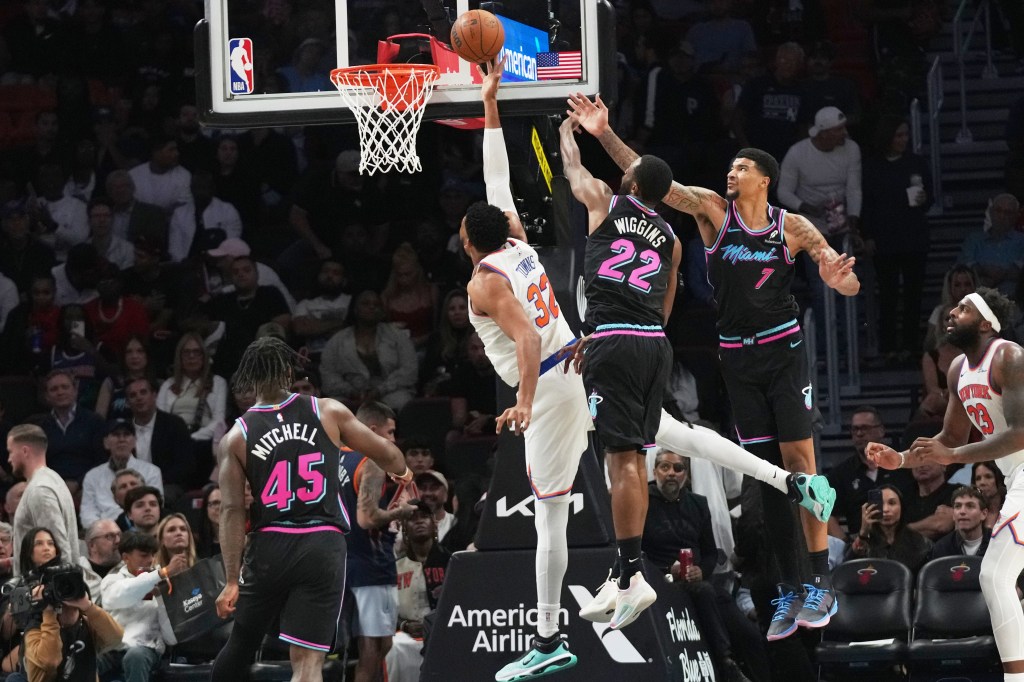 New York Knicks center Karl-Anthony Towns (32) shoots the ball as Miami Heat forward Andrew Wiggins (22) and center Kel'el Ware (7) defend.