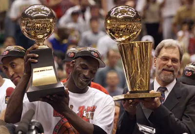 Michael Jordan holds the MVP trophy and coach Phil Jackson holds the championship trophy after the Bulls beat the Jazz to win their sixth title in 1998.