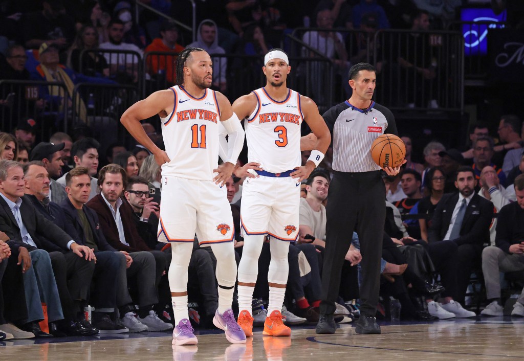 New York Knicks players Jalen Brunson (#11) and Josh Hart (#3) reacting on the court alongside a referee holding a basketball.