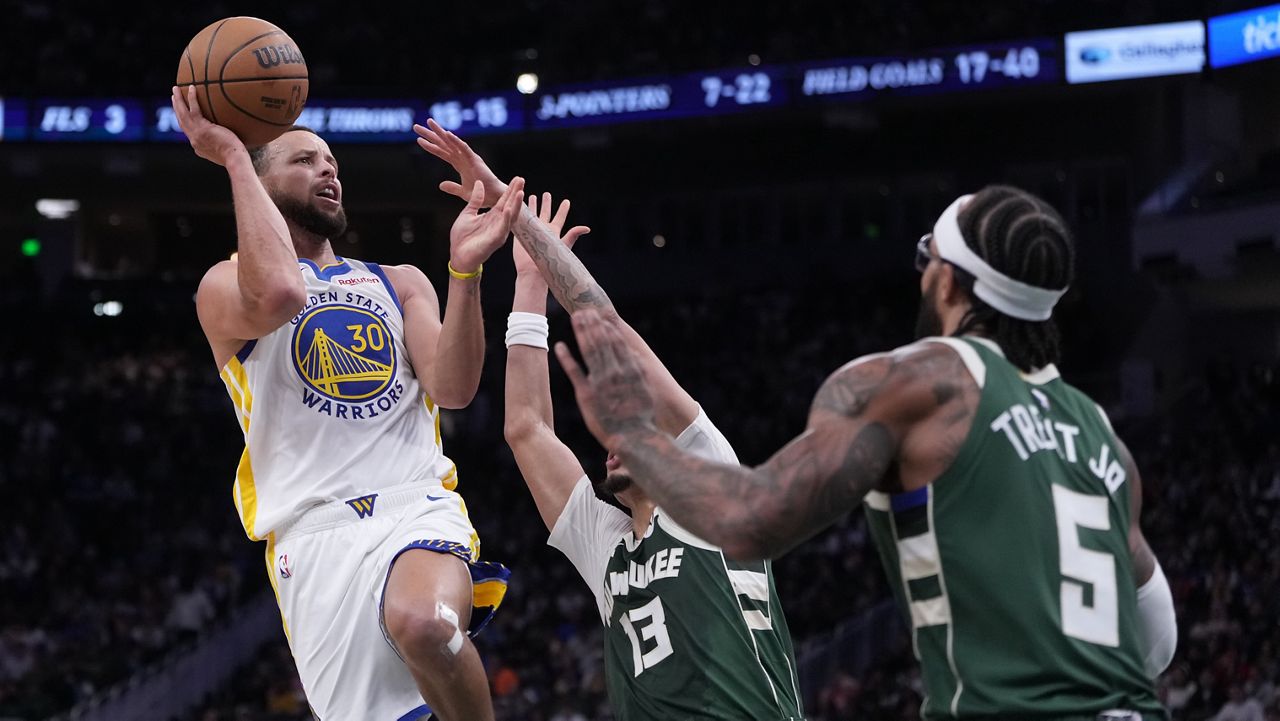 Golden State Warriors' Stephen Curry shoots past Milwaukee Bucks' Ryan Rollins and Gary Trent Jr. during the first half of an NBA basketball game Thursday, Oct. 30, 2025, in Milwaukee.