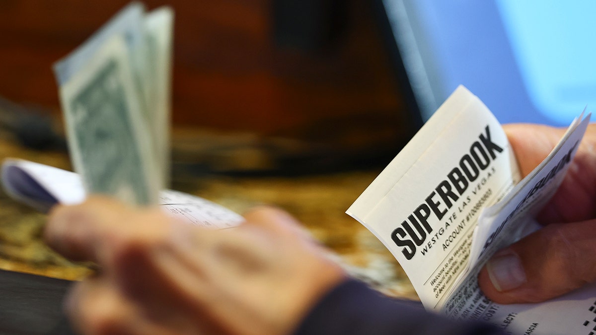 Gambler holds cash and sportsbook ticket