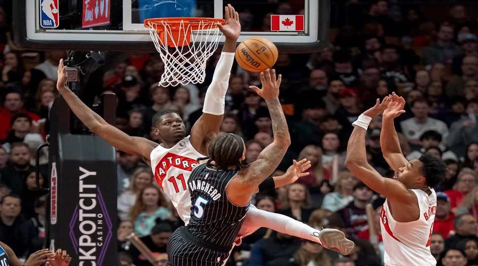Toronto Raptors center Mo Bamba (11) and forward Scottie Barnes, right, defend against Orlando Magic forward Paolo Banchero (5) as he shoots during first half NBA action in Toronto on Monday Dec. 29, 2025. THE (Frank Gunn/The Canadian Press via AP)