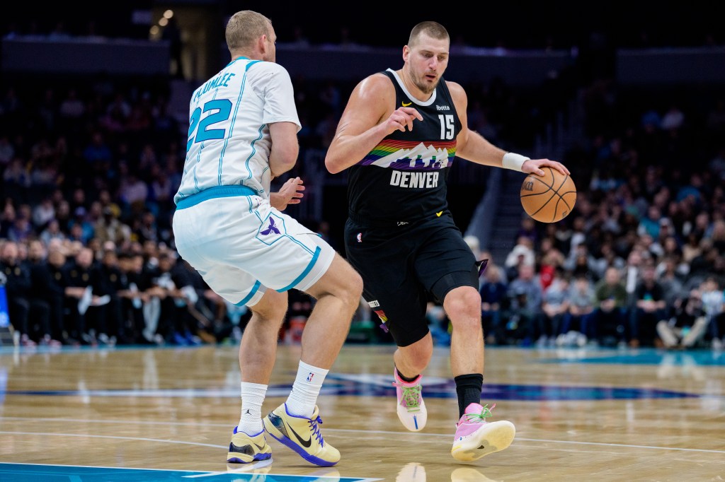 Nikola Jokic of the Denver Nuggets dribbles the basketball while Mason Plumlee of the Charlotte Hornets guards him.