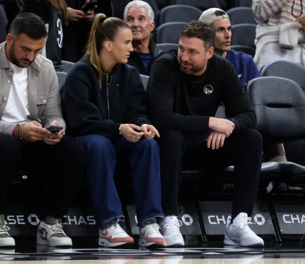 Sabrina Ionescu, left, with her husband Hroniss Grasu, far left, chats with Golden State Warriors assistant coach Chris DeMarco before the Warriors game against the Utah Jazz at the Chase Center in San Francisco, Calif., on Monday, Nov. 24, 2025. (Nhat V. Meyer/Bay Area News Group)