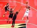 Mikal Bridges of the New York Knicks puts up a shot over Jakob Poeltl #19, Sandro Mamukelashvili #54 and Scottie Barnes #4 of the Toronto Raptors.