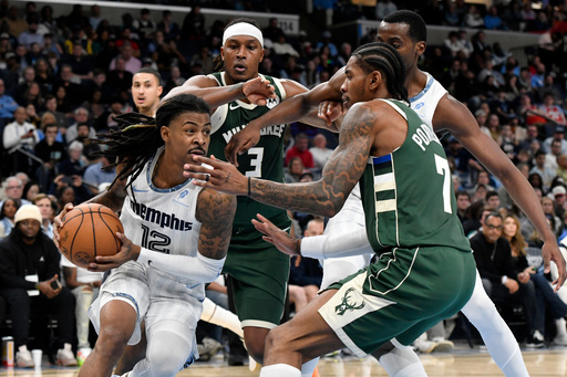 Memphis Grizzlies guard Ja Morant (12) drives against Milwaukee Bucks guard Kevin Porter Jr. (7) as Bucks center Myles Turner (3) and Grizzlies center Christian Koloko, back right, move for position in the first half of an NBA basketball game Friday, Dec. 26, 2025, in Memphis, Tenn. (AP Photo/Brandon Dill)