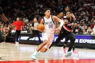 Dallas Mavericks guard Max Christie, middle, dribbles to the basket during the first half of...