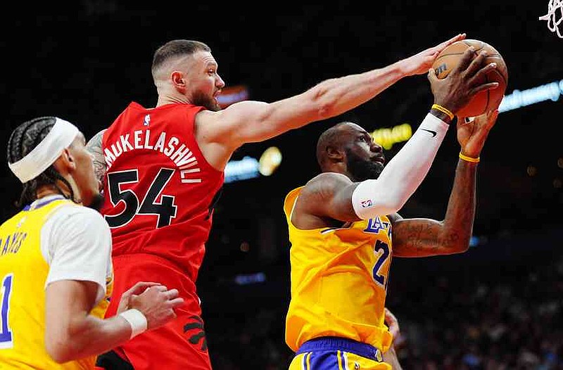 Los Angeles Lakers' LeBron James (right) drives to the basket as Toronto Raptors' Sandro Mamukelashvili (54) defends during second half NBA basketball action in Toronto on Thursday, Dec. 4, 2025. THE CANADIAN PRESS/Frank Gunn/The Canadian Press via AP)