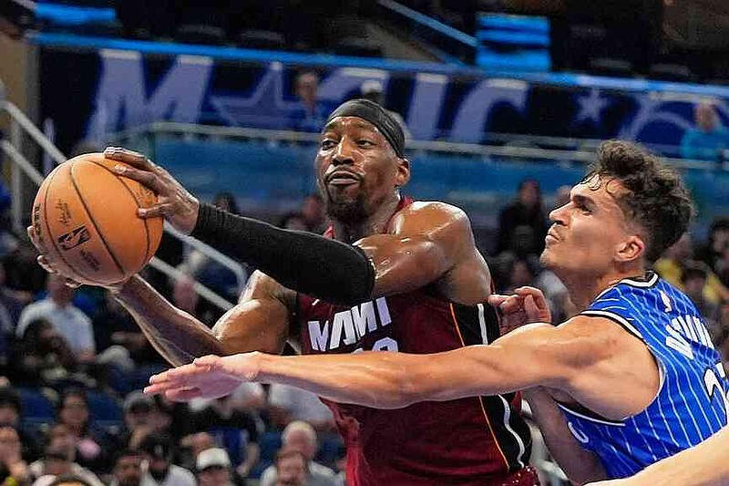 Miami Heat center Bam Adebayo, left, grabs a rebound away from Orlando Magic forward Tristan da Silva during the second half of an NBA basketball game, Friday, Dec. 5, 2025, in Orlando, Fla. (AP Photo/John Raoux)