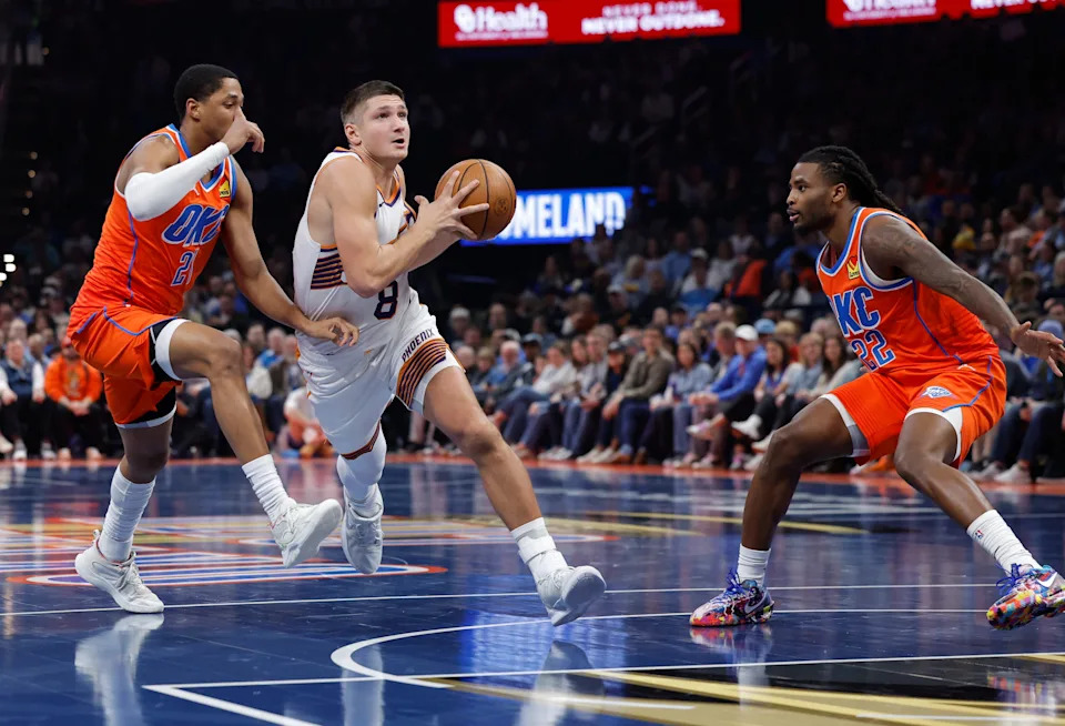 Dec 10, 2025; Oklahoma City, Oklahoma, USA; Phoenix Suns guard Grayson Allen (8) drives between Oklahoma City Thunder guard Aaron Wiggins (21) and guard Cason Wallace (22) during the second quarter at Paycom Center. Mandatory Credit: Alonzo Adams-Imagn Images