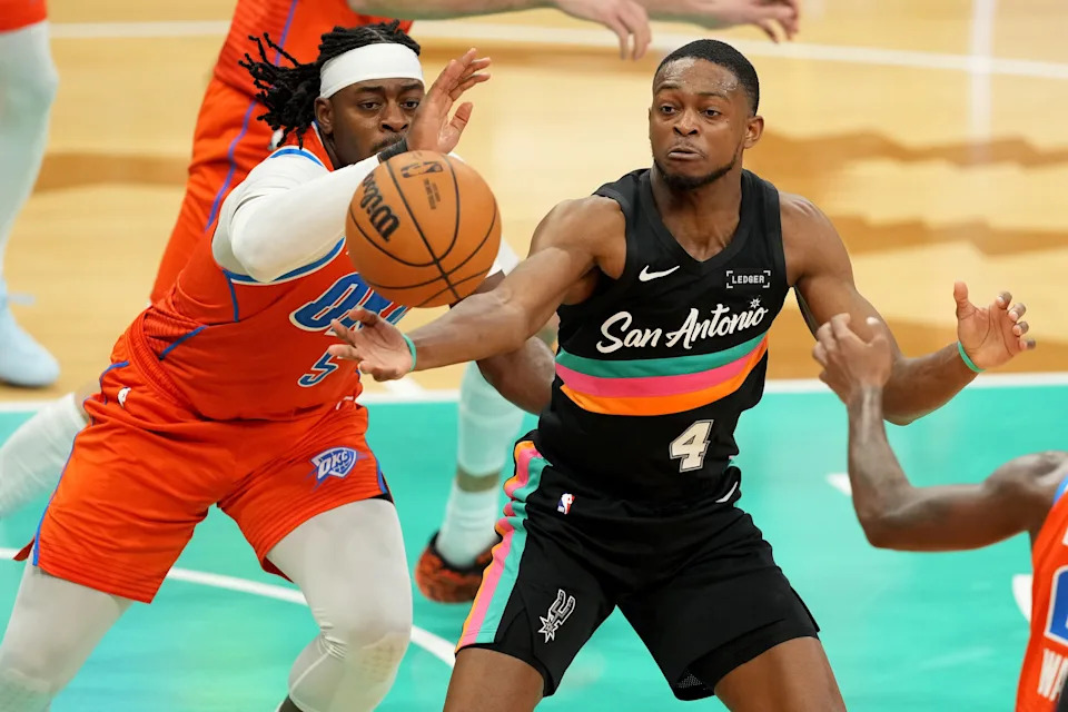 Dec 23, 2025; San Antonio, Texas, USA; San Antonio Spurs guard De’Aaron Fox (4) and Oklahoma City Thunder guard Luguentz Dort (5) reach for a loose ball during the first half at Frost Bank Center. Mandatory Credit: Scott Wachter-Imagn Images