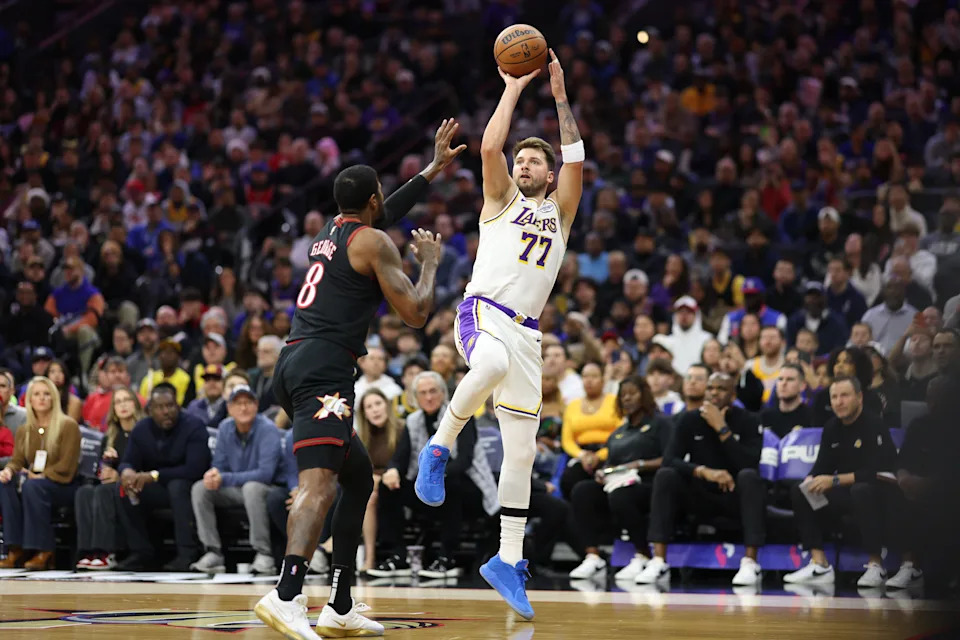 Dec 7, 2025; Philadelphia, Pennsylvania, USA; Los Angeles Lakers guard Luka Doncic (77) shoots against Philadelphia 76ers forward Paul George (8) during the first quarter at Xfinity Mobile Arena. Mandatory Credit: Bill Streicher-Imagn Images