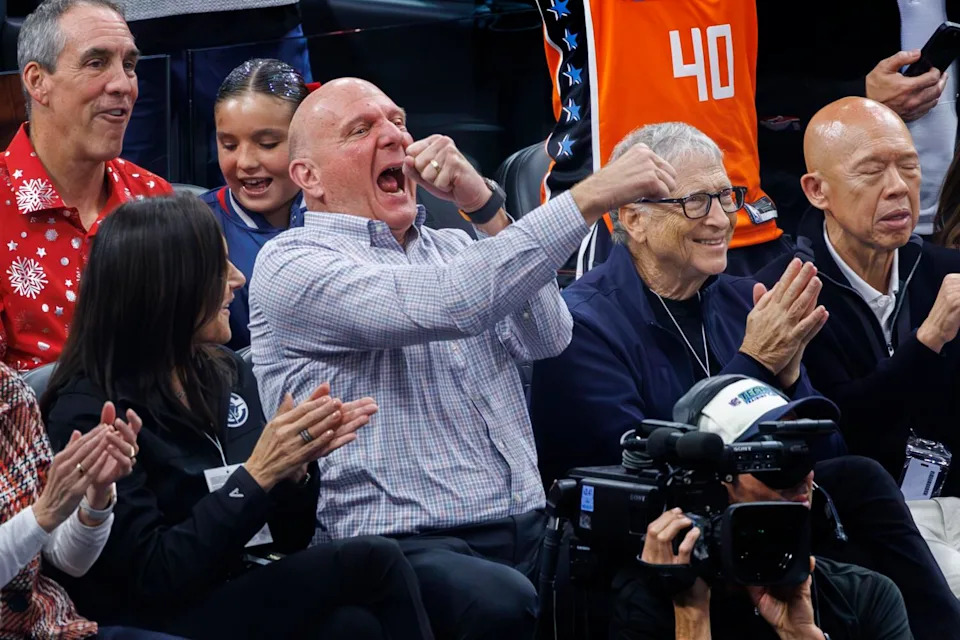 Clippers owner Steve Ballmer shouts and lifts his fists as Bill Gates applauds next to him.