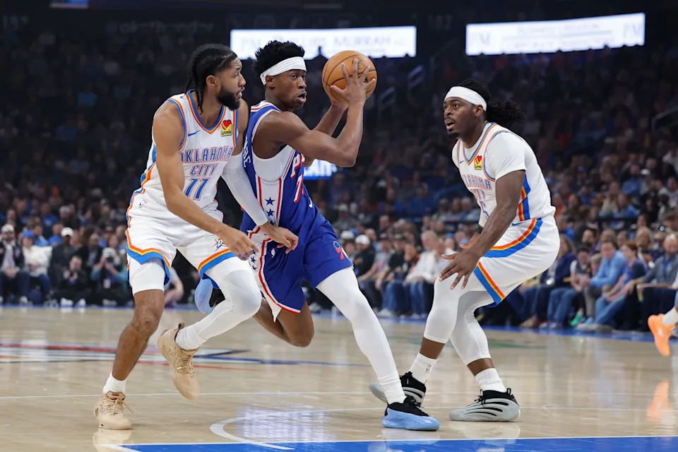 Dec 28, 2025; Oklahoma City, Oklahoma, USA; Philadelphia 76ers guard Vj Edgecombe (77) drives between Oklahoma City Thunder guard Isaiah Joe (11) and guard Luguentz Dort (5) during the first quarter at Paycom Center. Mandatory Credit: Alonzo Adams-Imagn Images
