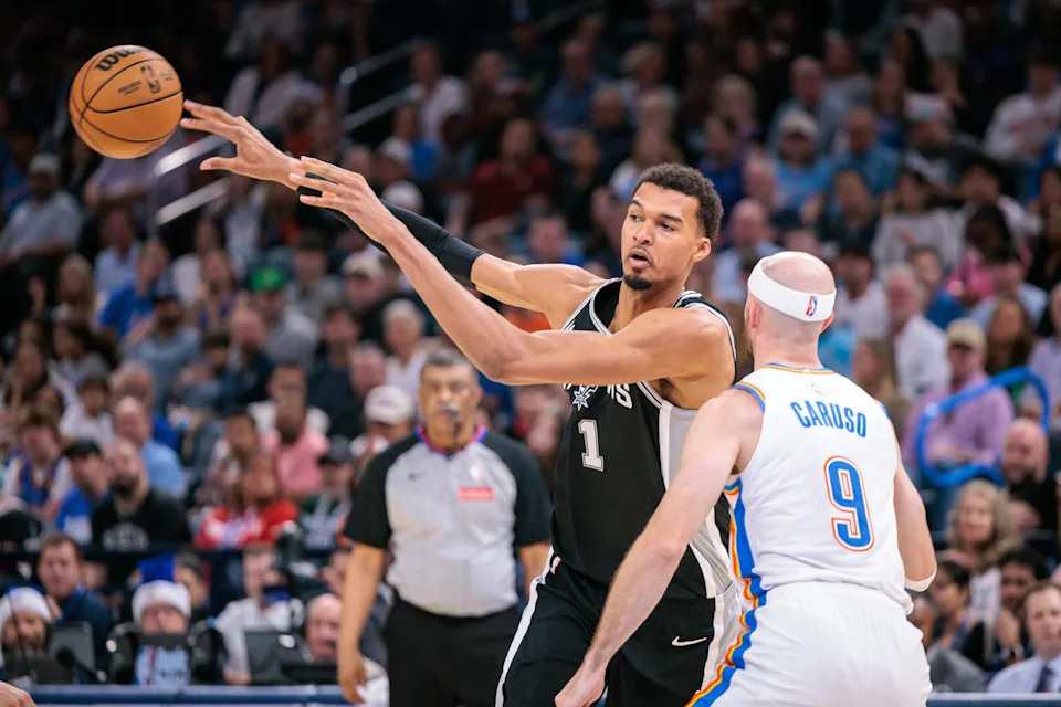 OKLAHOMA CITY, OKLAHOMA - DECEMBER 25: Victor Wembanyama #1 of the San Antonio Spurs passes the ball around Alex Caruso #9 of the Oklahoma City Thunder during the second half at Paycom Center on December 25, 2025 in Oklahoma City, Oklahoma. NOTE TO USER: User expressly acknowledges and agrees that, by downloading and or using this photograph, User is consenting to the terms and conditions of the Getty Images License Agreement. (Photo by William Purnell/Getty Images)
