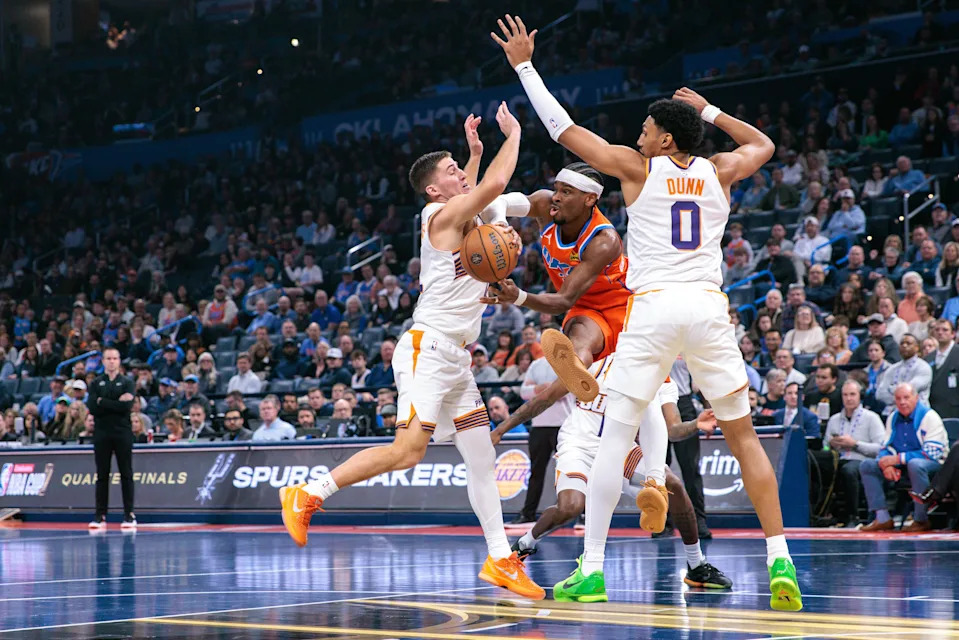 OKLAHOMA CITY, OKLAHOMA - DECEMBER 10: Shai Gilgeous-Alexander #2 of the Oklahoma City Thunder passes the ball against Nigel Hayes-Davis #21 and Ryan Dunn #0 of the Phoenix Suns during the first half of the Emirates NBA Cup - Quarterfinals game at Paycom Center on December 10, 2025 in Oklahoma City, Oklahoma. NOTE TO USER: User expressly acknowledges and agrees that, by downloading and or using this photograph, User is consenting to the terms and conditions of the Getty Images License Agreement. (Photo by William Purnell/Getty Images)