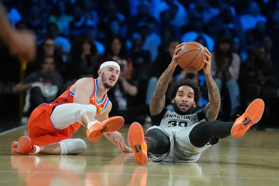 Dec 13, 2025; Las Vegas, Nevada, USA; San Antonio Spurs forward Julian Champagnie (30) grabs the loose ball from Oklahoma City Thunder guard Alex Caruso (9) during the third quarter at T-Mobile Arena. Mandatory Credit: Kirby Lee-Imagn Images