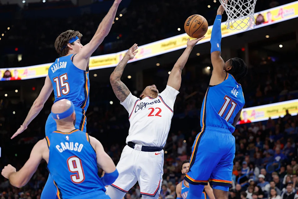 Dec 18, 2025; Oklahoma City, Oklahoma, USA; Los Angeles Clippers guard Jordan Miller (22) shoots between Oklahoma City Thunder center Branden Carlson (15) and guard Isaiah Joe (11) during the second half at Paycom Center. Mandatory Credit: Alonzo Adams-Imagn Images