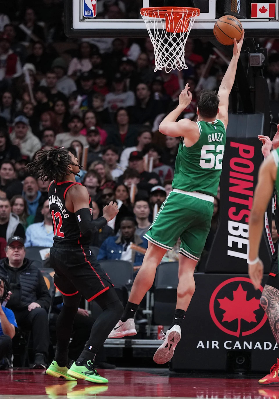 Dec 20, 2025; Toronto, Ontario, CAN; Boston Celtics center Luka Garza (52) drives to the basket over Toronto Raptors forward Collin Murray-Boyles (12) during the third quarter at Scotiabank Arena. Mandatory Credit: Nick Turchiaro-Imagn Images