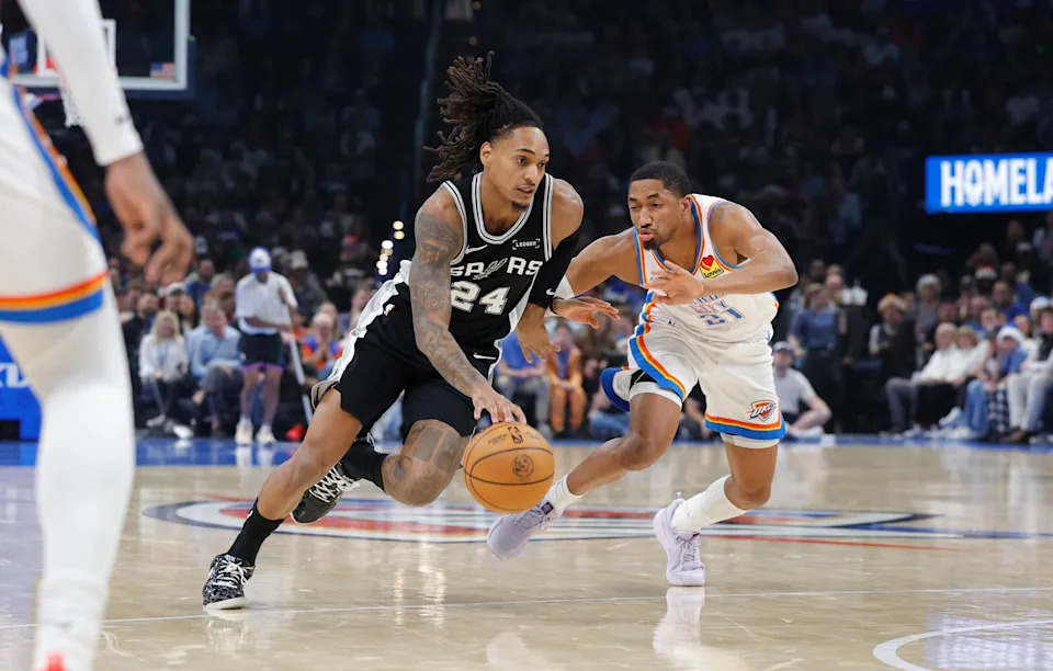 Dec 25, 2025; Oklahoma City, Oklahoma, USA; San Antonio Spurs guard Devin Vassell (24) drives to the basket beside Oklahoma City Thunder guard Aaron Wiggins (21) during the second quarter at Paycom Center. Mandatory Credit: Alonzo Adams-Imagn Images