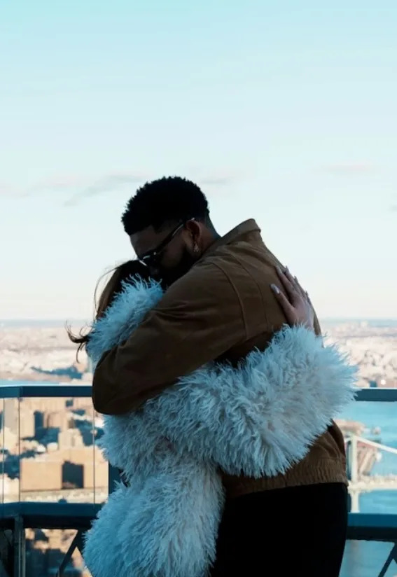 Jordyn Woods and Karl-Anthony Towns embracing on a New York City rooftop following their engagement
